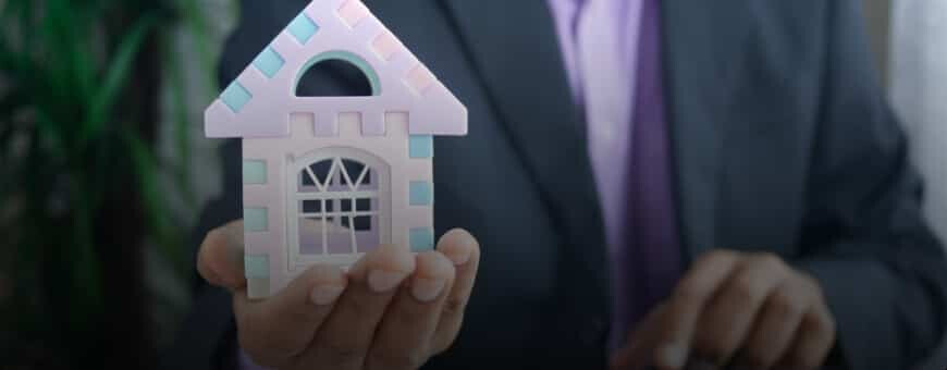 A professional holding a toy house in his hand