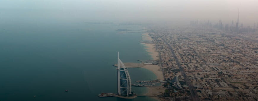 The Burj Al Arab standing between the urban landscape and the sea in Abu Dhabi