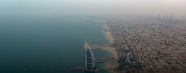 The Burj Al Arab standing between the urban landscape and the sea in Abu Dhabi.