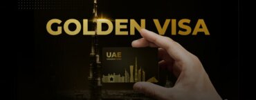 A person holding a Golden Visa card with gold letters saying "Golden Visa" and the Burj Khalifa in the background.